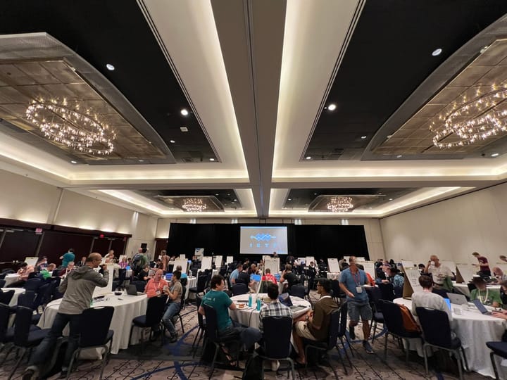 large conference room with people around tables full of computers