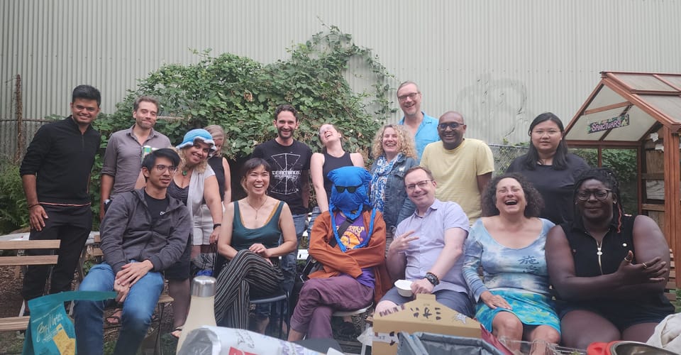 group shot of 16 people laughing and smiling in an outdoor setting