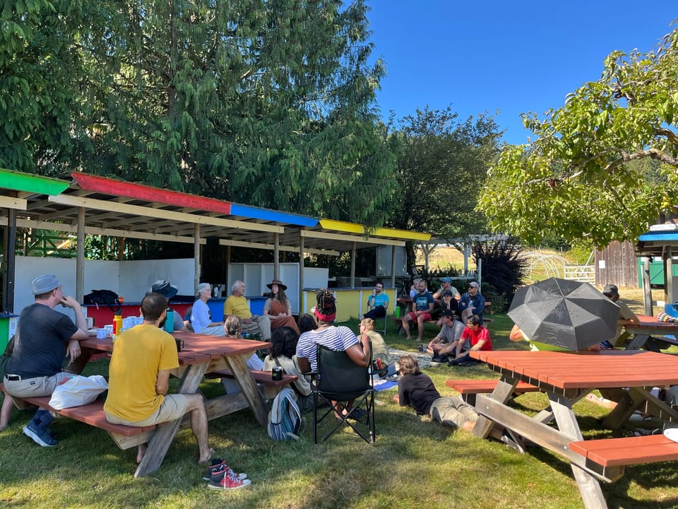 People at Cascadia Camp 2025 sitting on benches and on the ground in conversation